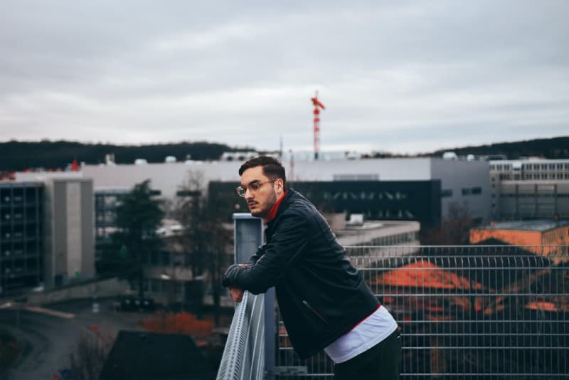 man with eyeglasses standing besides railings