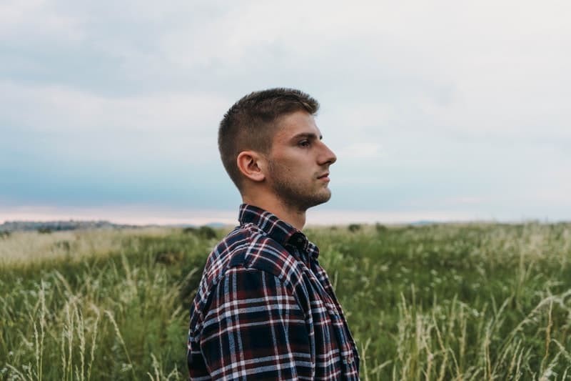 homem de pé num campo de relva com vista lateral