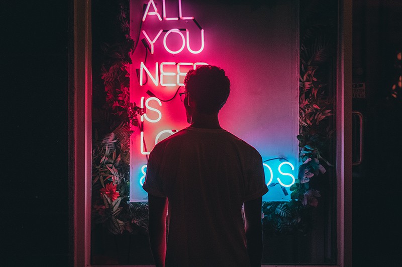man standing in front of neon lights with letters