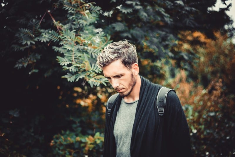 man with backpack standing near tree at daytime