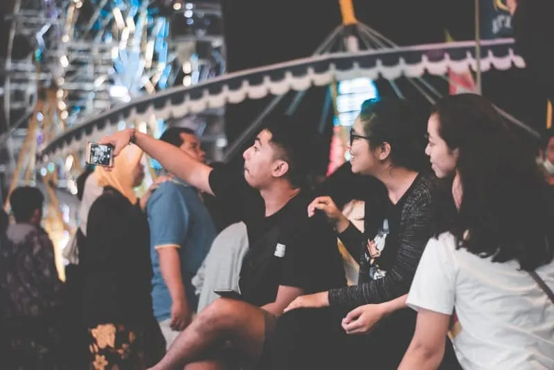 man in black shirt taking selfie in amusement park