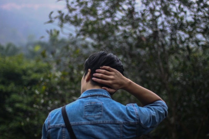 uomo con giacca di jeans blu che si tocca i capelli