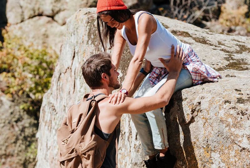 man trying to help a woman getting down holding her hips