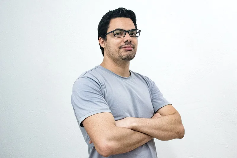 man wearing glasses and grey t-shirt crossing both arms