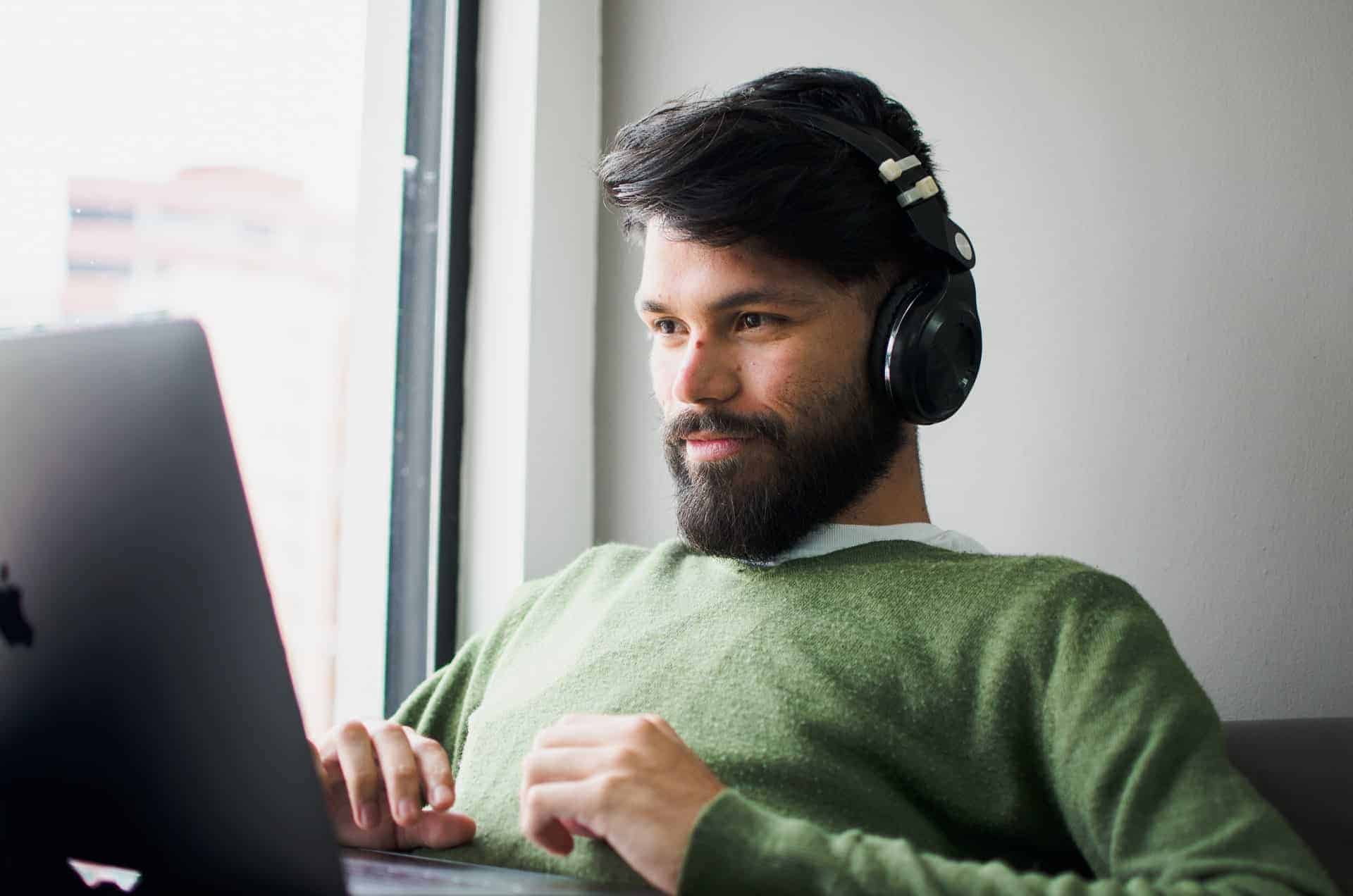 hombre con jersey verde usando ordenador portátil