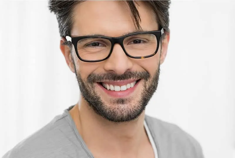man with beard smiling wearing eyeglasses and gray shirt