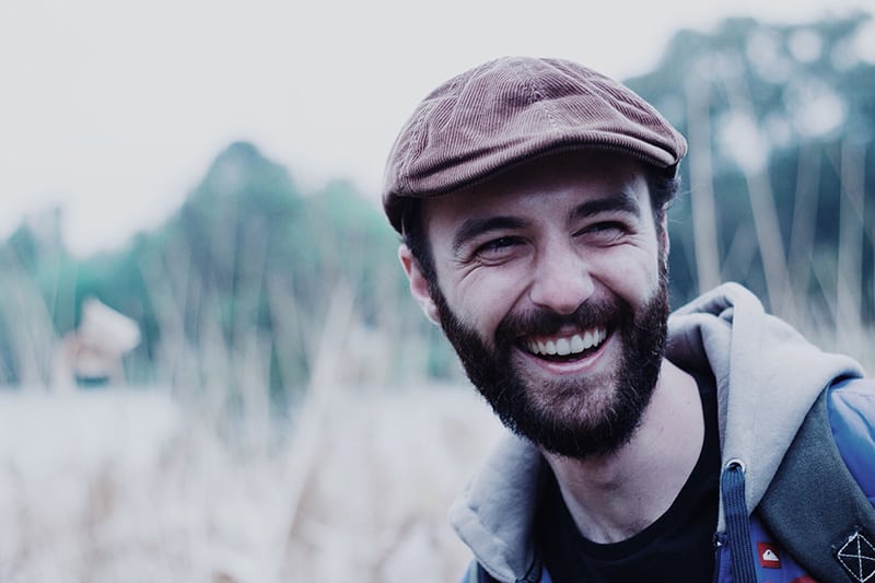 hombre con gorra marrón sonriendo en el campo