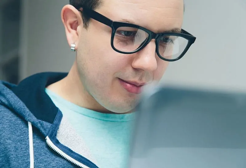 man with eyeglass facing a laptop
