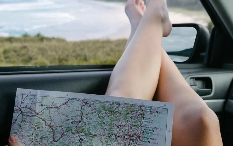 Map on woman legs on car window during daytime