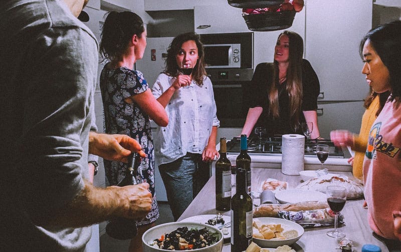 hombres y mujeres de pie junto a la mesa llena de comida