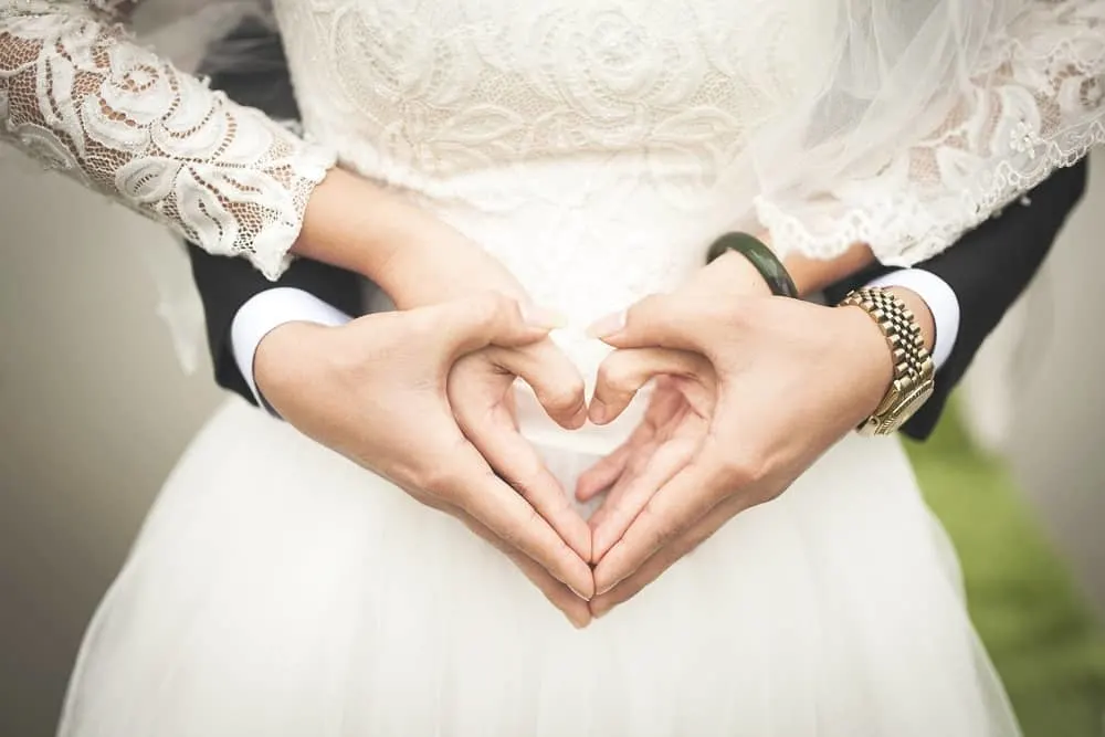 midsection of married couple making heartshape hands