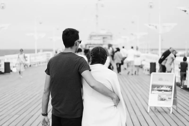 Monochrome couple man hug woman on boardwalk