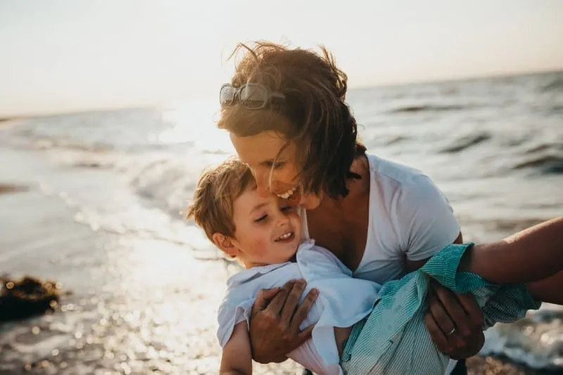 woman holding boy near water