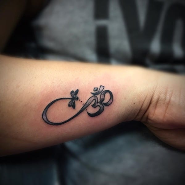 segno om con libellula tatuaggio sul braccio