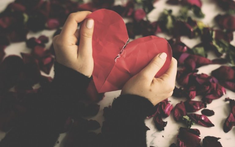 Hands holding red paper broken heart
