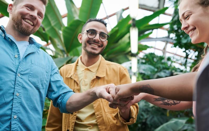 One woman and two men doing fist bump