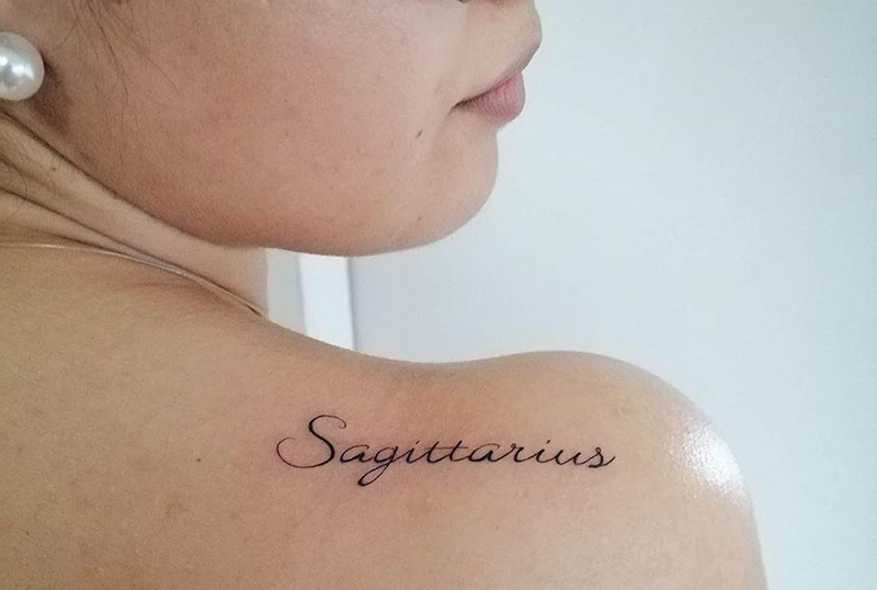 tatuaje de una palabra de sagitario en la espalda de una mujer