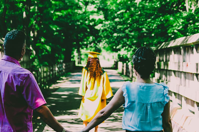 parents looking at their daughter in yellow academic dress