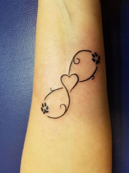 tatuaggio con disegno di zampe e cuore sul braccio