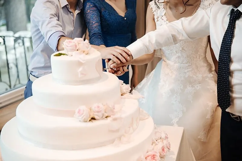 people cutting wedding cake with newlyweds
