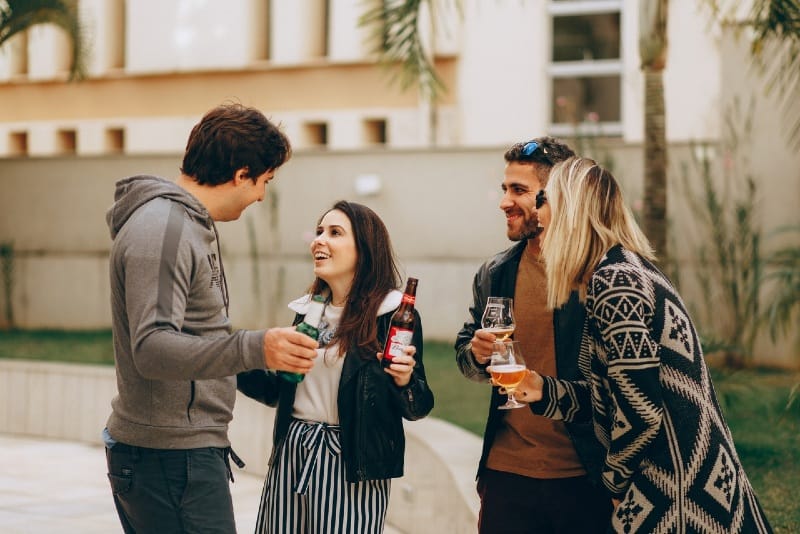 quatro pessoas a beberem bebidas em pé ao ar livre