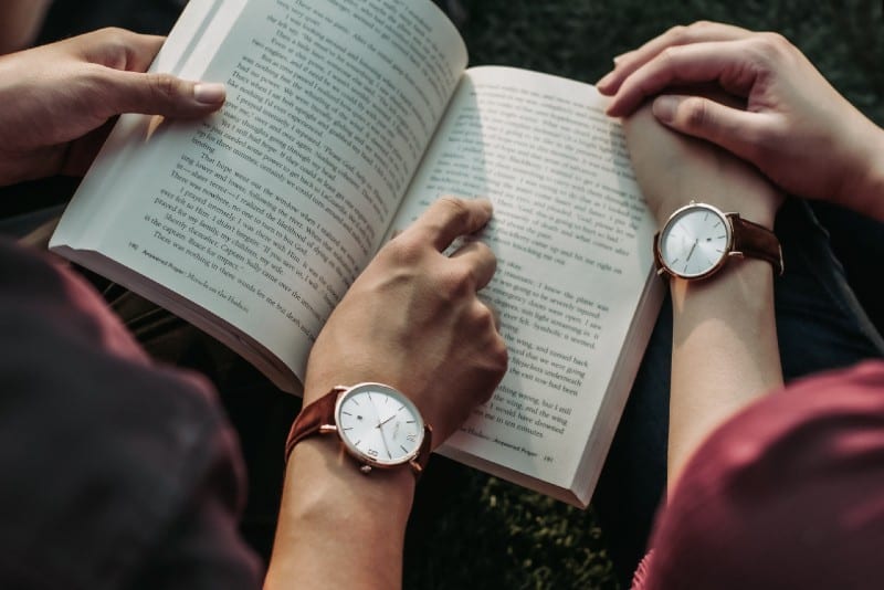 two people with watches reading book