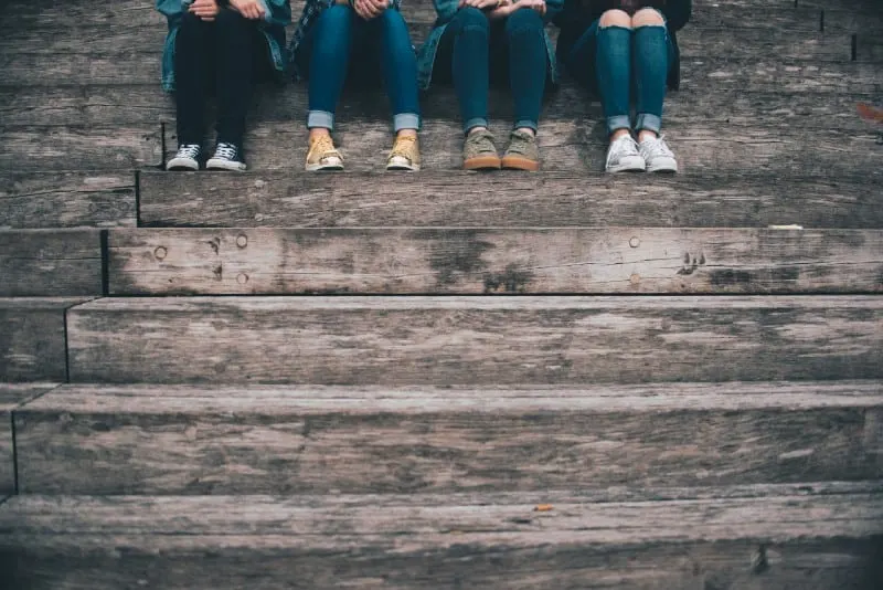 four people sitting on wooden stairs