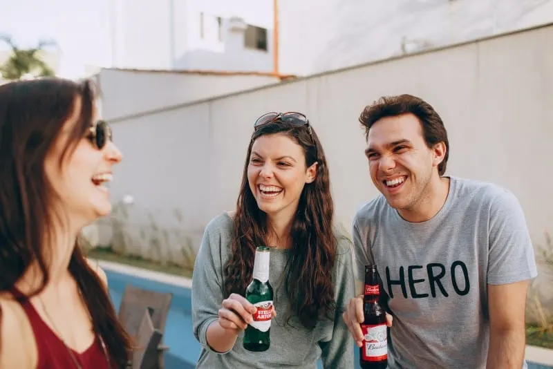 three people smiling and drinking outdoor