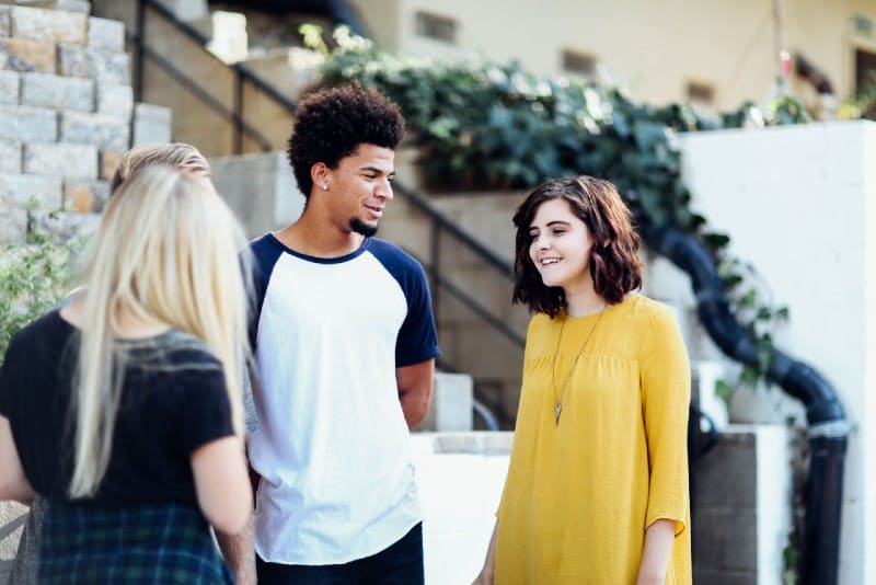 women and man standing and talking outside the building