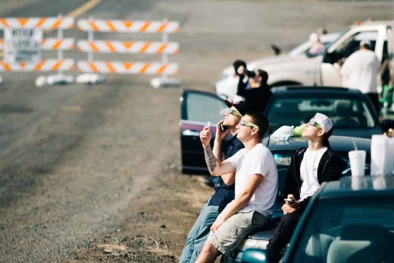 group of people sitting on car while watching eclipse