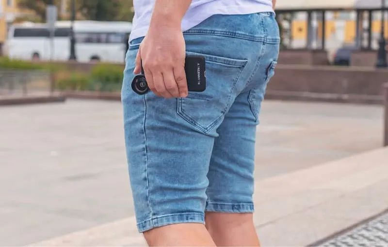 person carrying cellphone outside wearing knee denim shorts