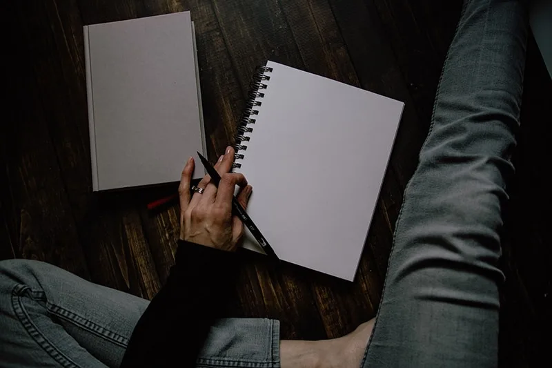 person holding black pen and notebook
