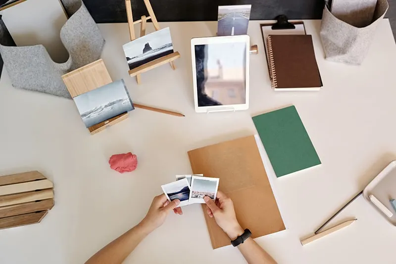 person holding instant pictures by the desk