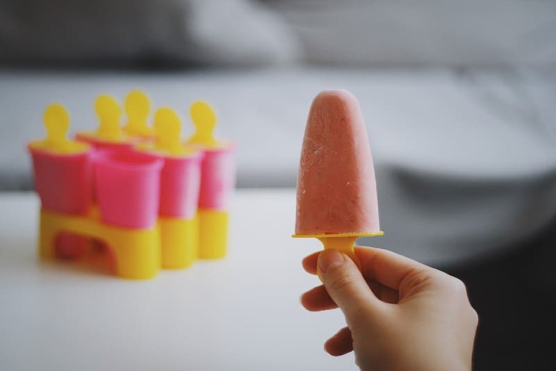 man holding orange popsicle ice cream