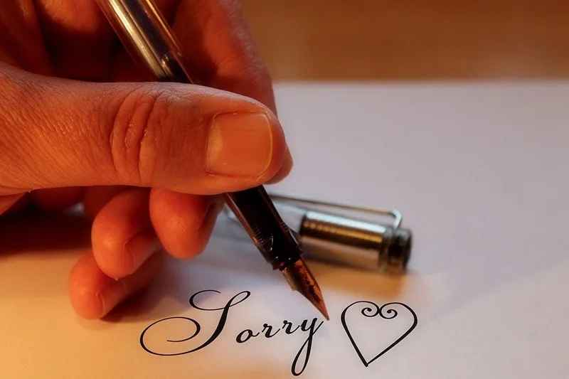 person holding the pen under the apology message