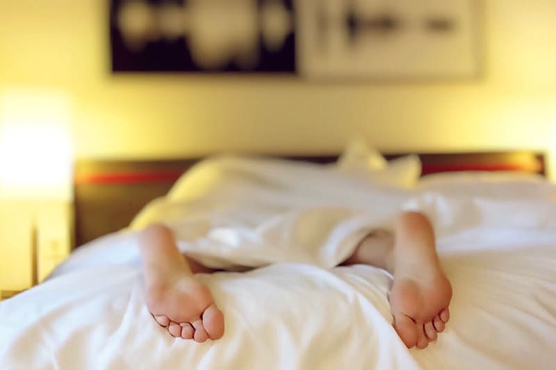 person lying on the bed covered with white blanket