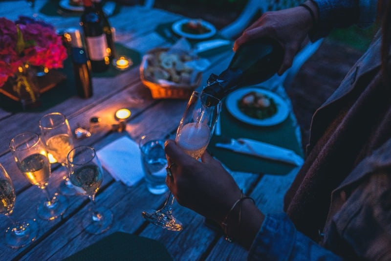 persona che mette lo champagne sul bicchiere flute la sera