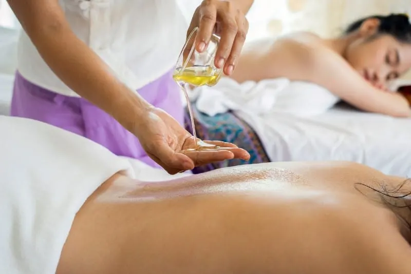 person pouring oil into hand before giving massage