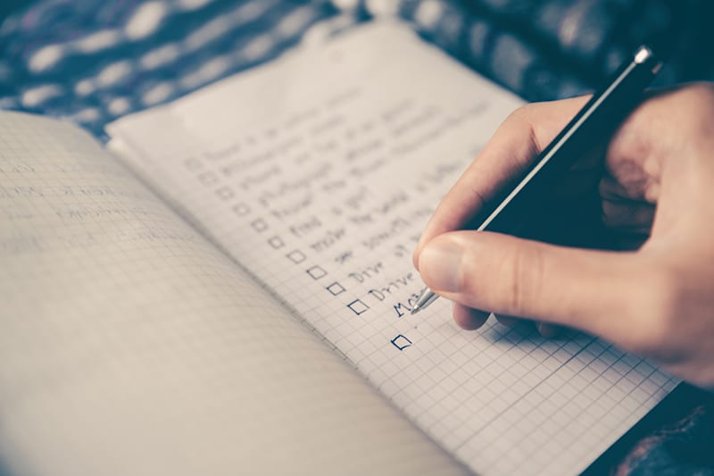 person writing bucket list on the notebook