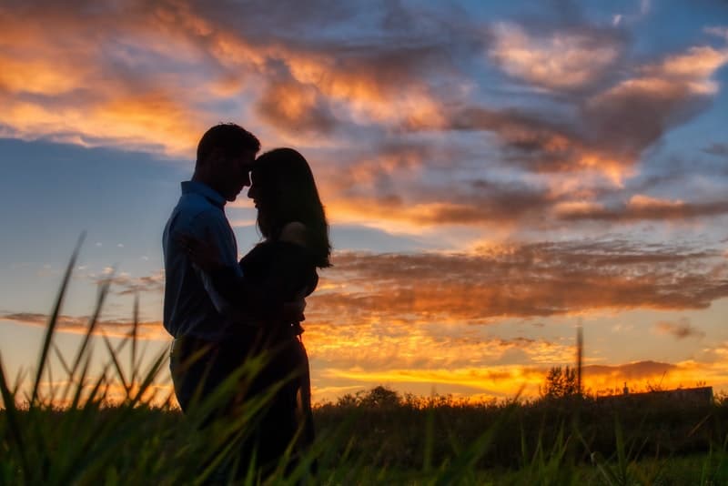 photo of couple hugging during dawn in the middle of the grassfields
