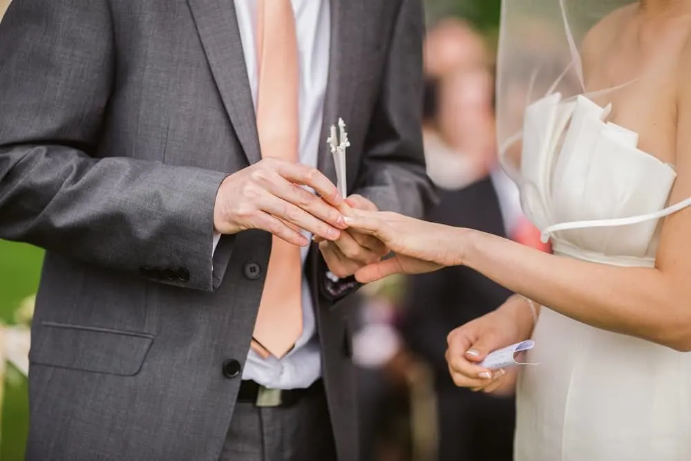 photo of a groom putting wedding ring on his bride