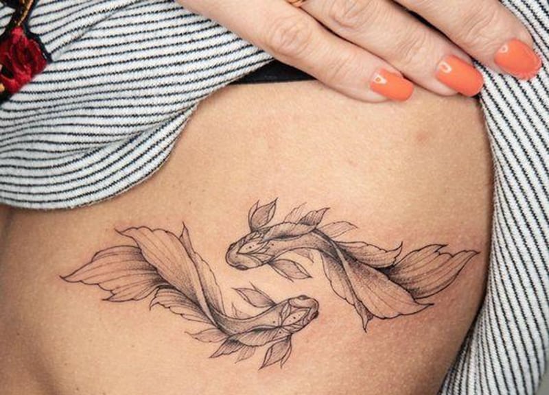 pisces tattoo with thin lines on the rib cage