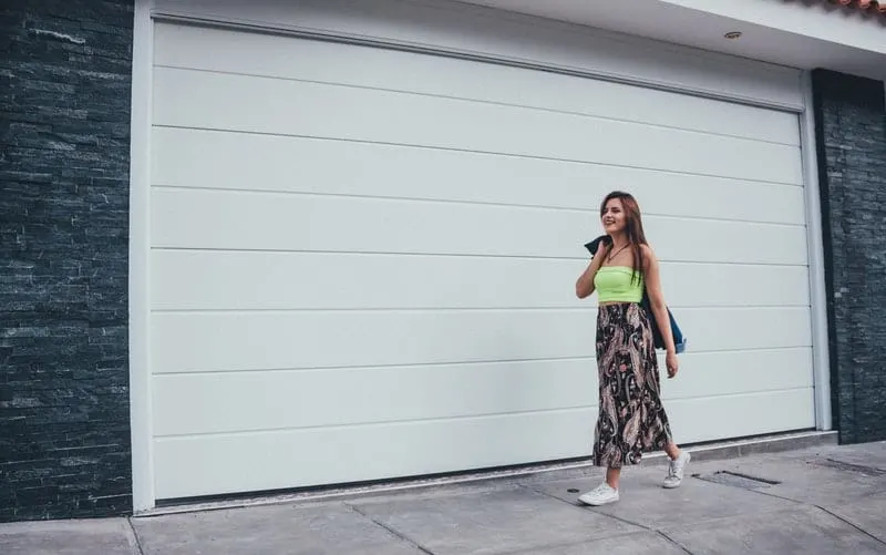 pretty woman walking on the sidewalk near white walls