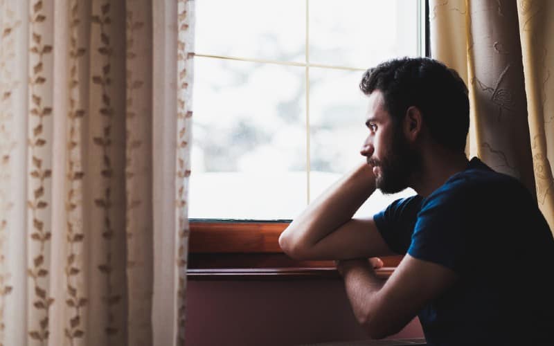 Homem triste sentado à janela