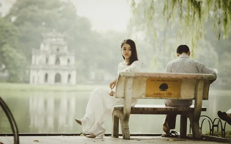 Sad woman and man sitting on a bench near a lake