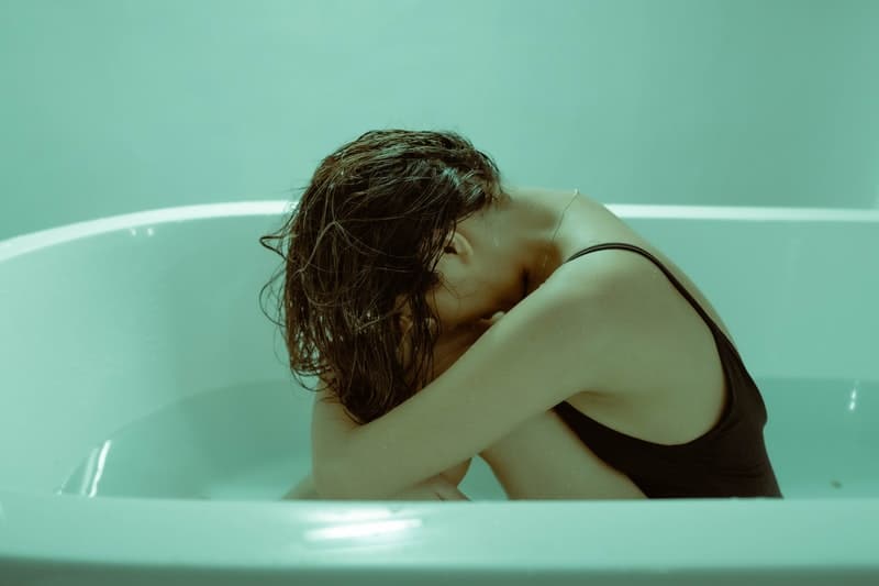 sad woman in tub wearing black sleeveless