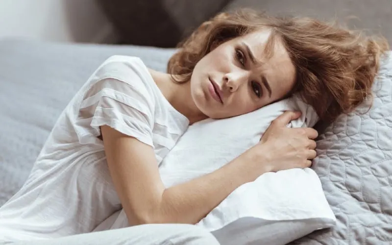 Beautiful sad young woman lying on a pillow