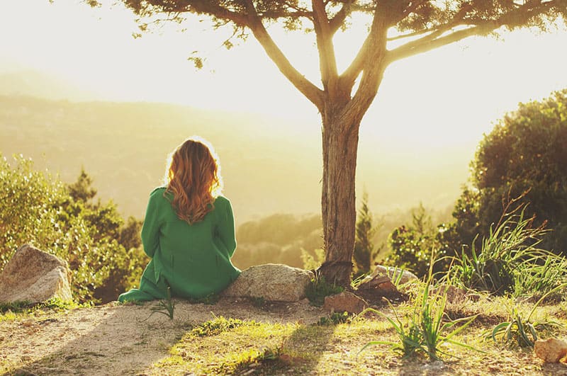 mujer triste sentada sola en la naturaleza