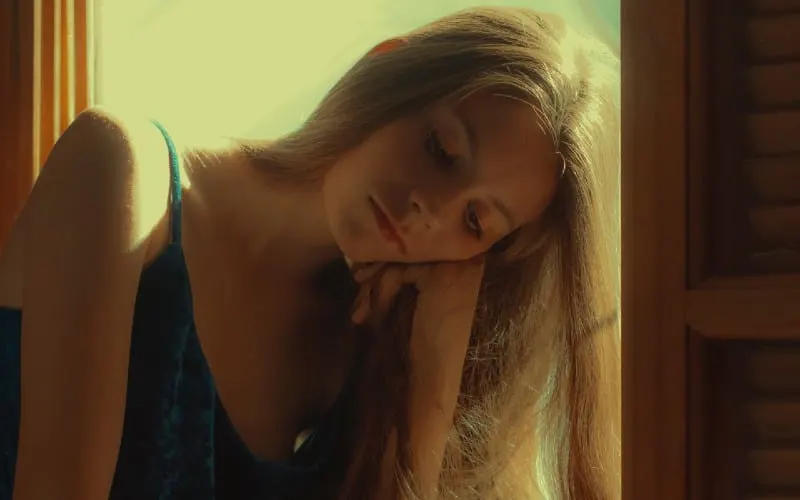 Sad woman in blue dress sitting at the window