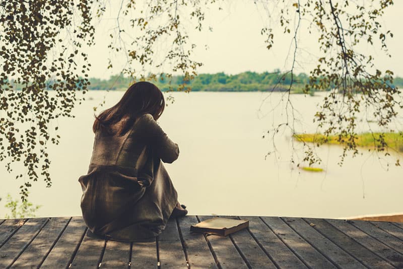sad woman sitting by the lake